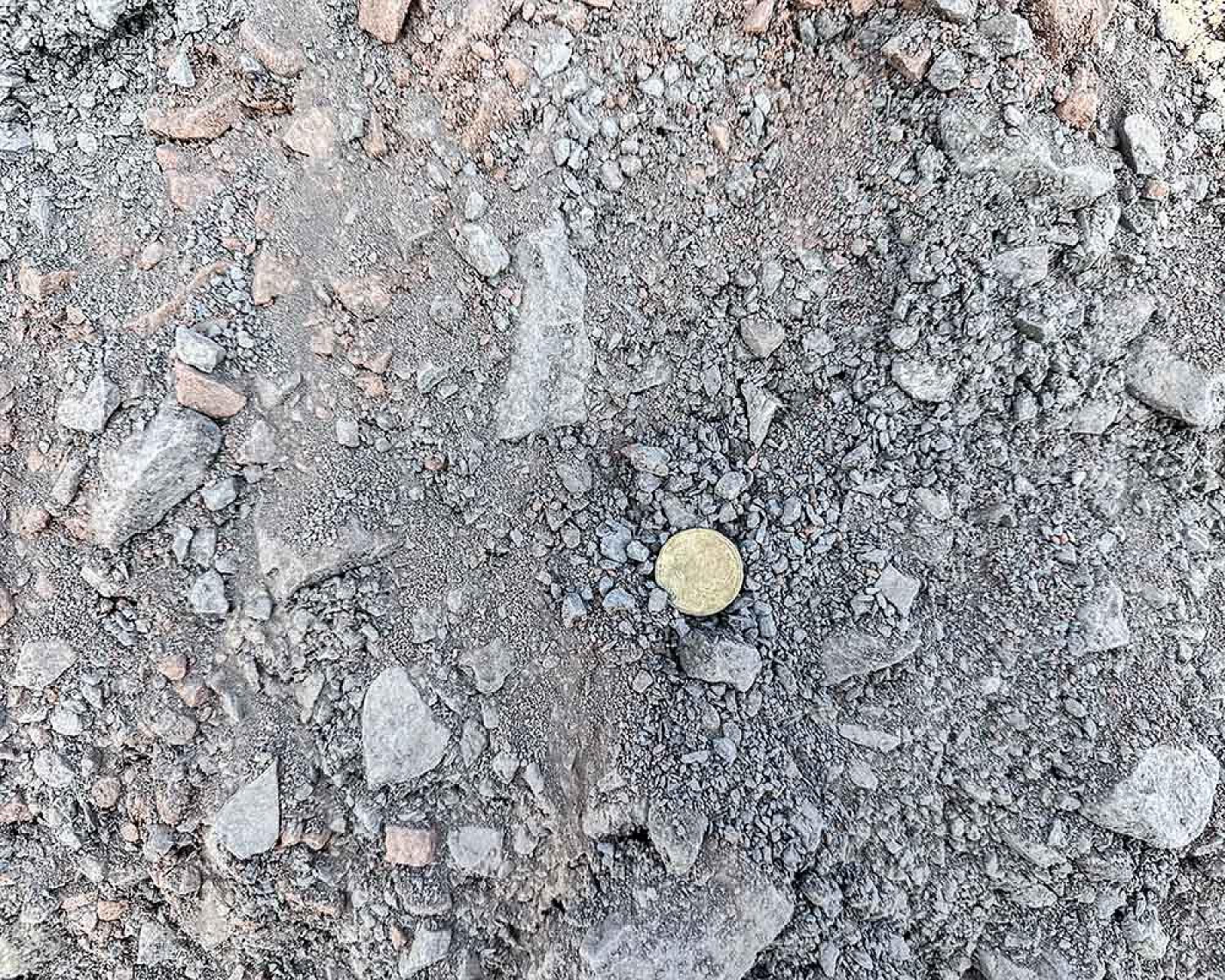 Schotter und Steine auf Bodenansicht, mit Münze für Größenvergleich. Natursteinmineralgemisch von Winfried Beiler GmbH.