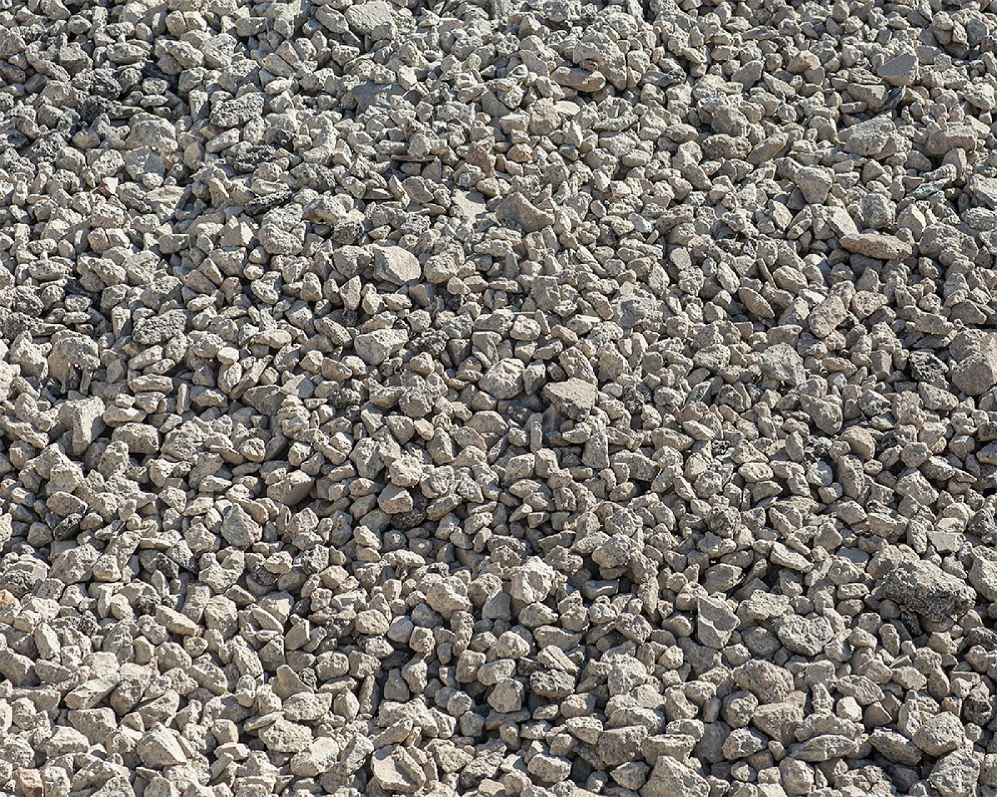 Haufen grauer Beton- und Recycling-Schotter in grober Körnung.