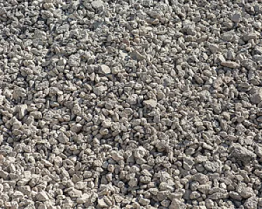 Haufen grauer Beton- und Recycling-Schotter in grober Körnung.