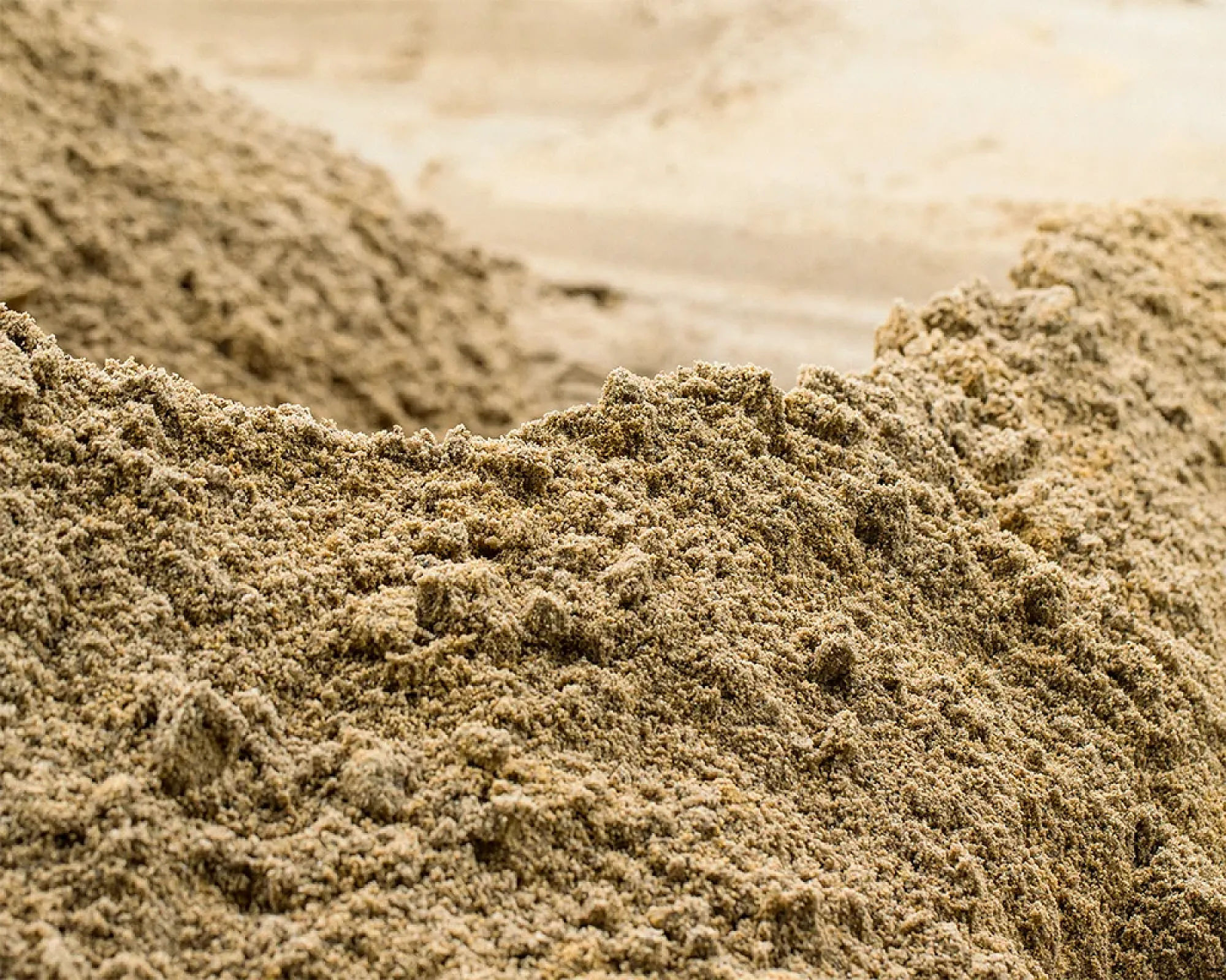 Gewaschener Sandhaufen in natürlicher Umgebung, präsentiert von Naturstein + Recycling Winfried Beiler GmbH.