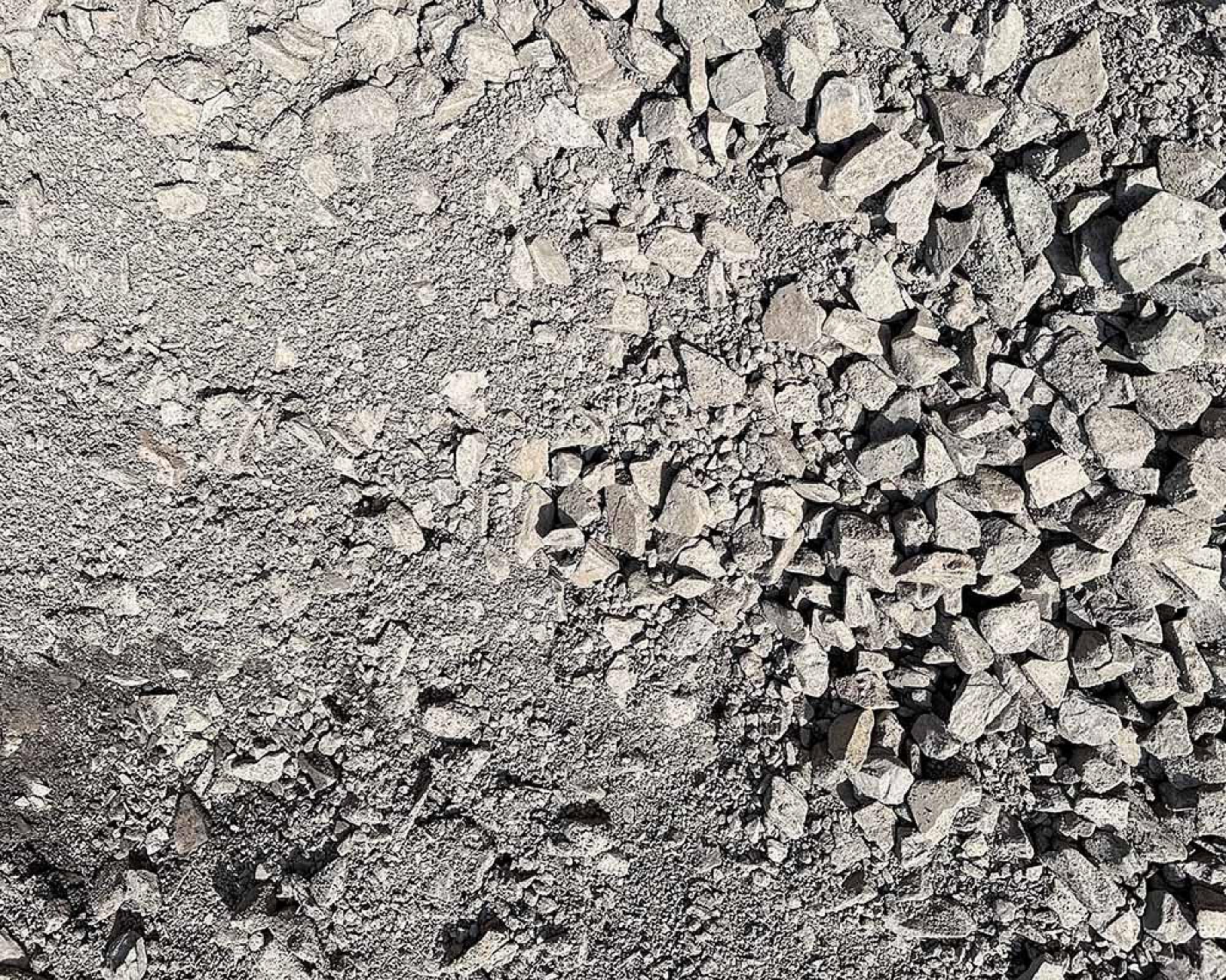 Steinhaufen aus grauem Mineralgemisch auf Baustelle.