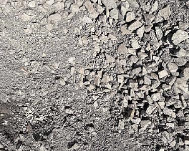 Steinhaufen aus grauem Mineralgemisch auf Baustelle.