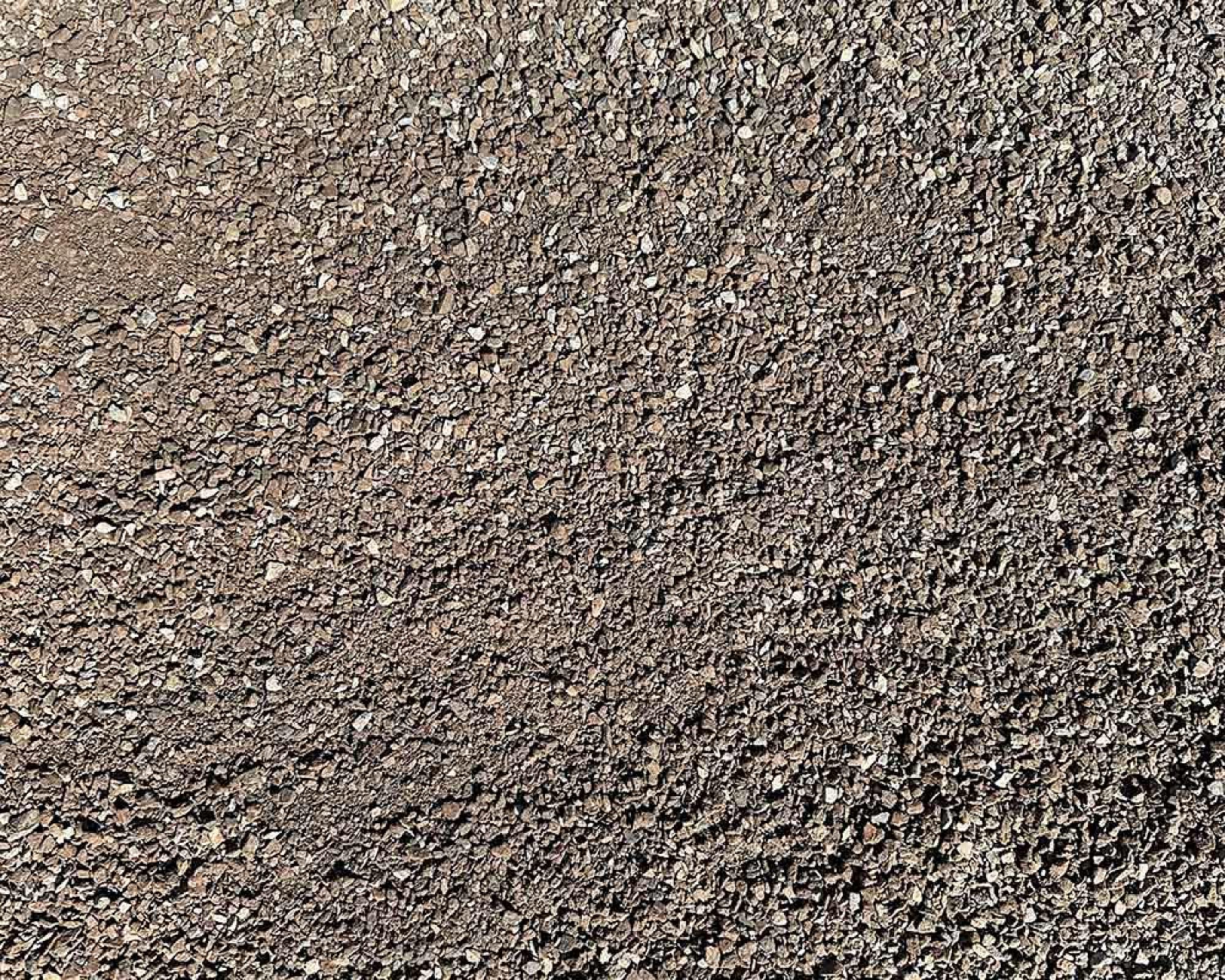 Nahaufnahme von grauem Fugensplitt aus Hartstein, gleichmäßig verteilt.