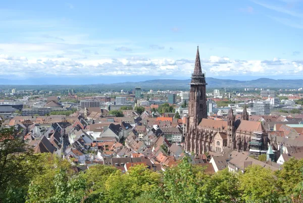 Panorama von Freiburg im Breisgau mit dem Münster und umliegender urbaner Landschaft bei klarem Himmel.