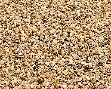 Quarzsand in Nahaufnahme, feine bis mittelgroße Körner, beige und hellbraun in unterschiedlichen Formen und Größen.