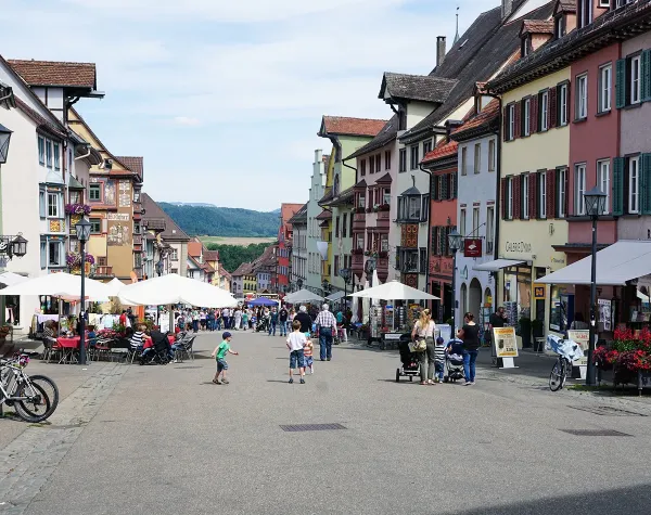Belebte Straße in Rottweil mit historischen Gebäuden, Cafés und Passanten.