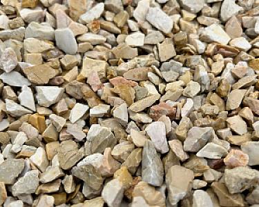 Beige-weißer Kalksteinsplitt in Nahaufnahme, verschiedene Größen und Formen der Steine sichtbar.