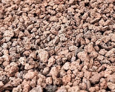 Nahaufnahme von rot-braunem Lavamulch mit ungleichmäßiger Körnung.