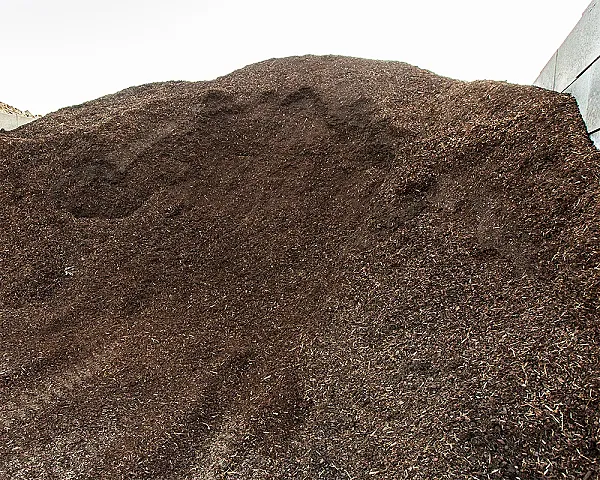 Ein großer Haufen feiner Rindenmulch in einem Lagerbereich.