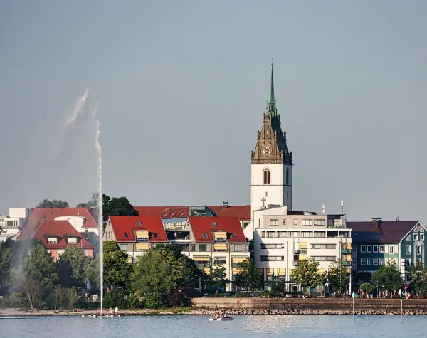 Stadtansicht von Friedrichshafen am Bodensee mit Rathaus und Springbrunnen im Vordergrund.