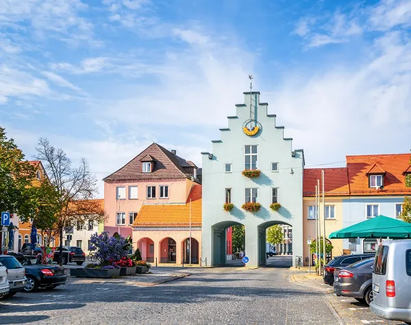 Alt-Text: Historisches Stadttor in Neumarkt in der Oberpfalz mit bunten Häusern und blauem Himmel im Hintergrund.