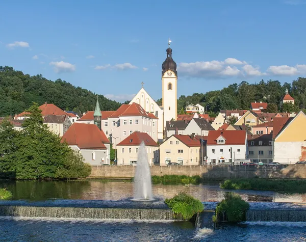 Kleinstadt Schwandorf mit Kirche, bunten Häusern und Springbrunnen im Vordergrund.