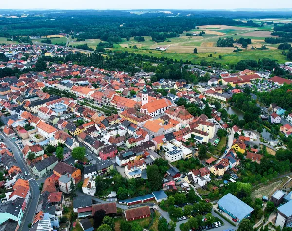 Luftaufnahme von Tirschenreuth, mit historischen Gebäuden, Kirche im Zentrum und grüner Umgebung im Hintergrund.
