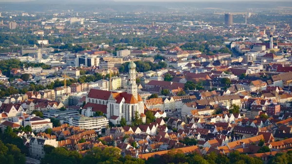 Luftaufnahme der Stadt Augsburg, dominiert von historischen Gebäuden und dem Augsburger Dom im Zentrum.
