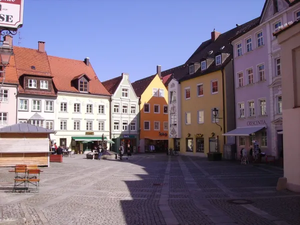 Historischer Marktplatz in Kaufbeuren mit bunten Fassaden und gepflastertem Boden bei sonnigem Wetter.