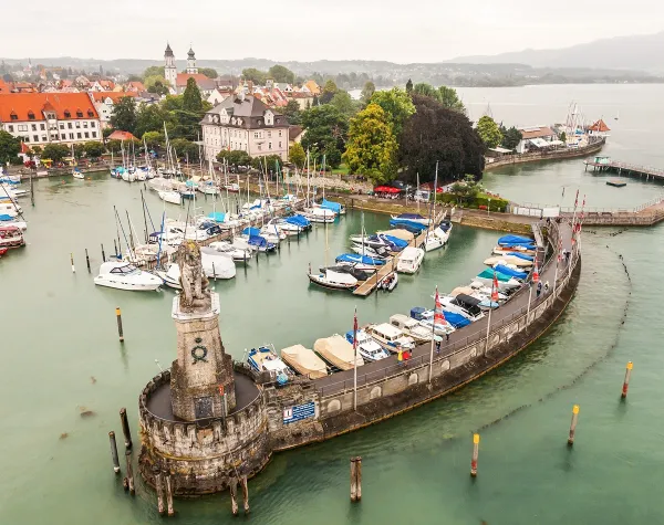 Hafen von Lindau am Bodensee mit Segelbooten, Leuchtturm und umliegenden historischen Gebäuden.