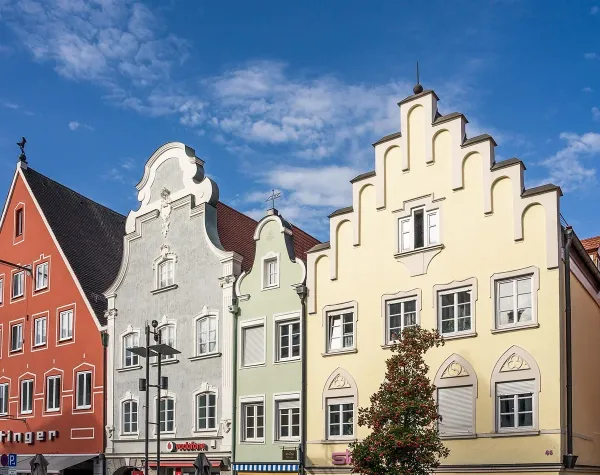 Bunte historische Häuser mit Treppengiebeln an einer Straße im Unterallgäu, blauer Himmel im Hintergrund.