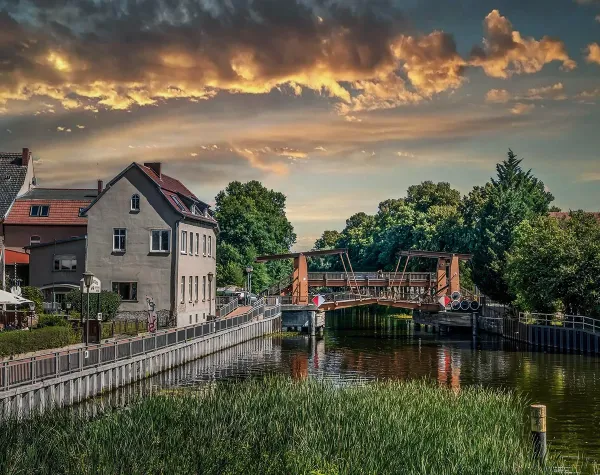 Historische Stadtansicht in Brandenburg an der Havel mit Fluss, Brücke und grüner Ufervegetation bei dramatischer Wolkenku...