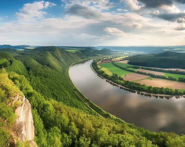 Panorama mit Blick auf den Fluss in einer grünen Landschaft von Elbe-Elster mit Wäldern und Feldern unter bewölktem Himmel.