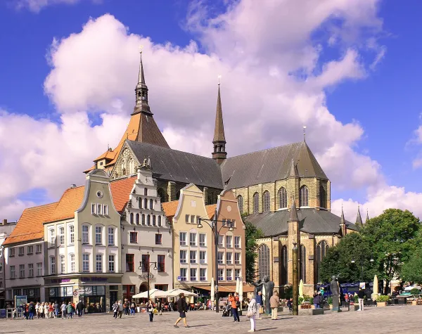 Historische Gebäude und Marienkirche auf dem Marktplatz in der Hansestadt Rostock unter blauem Himmel.