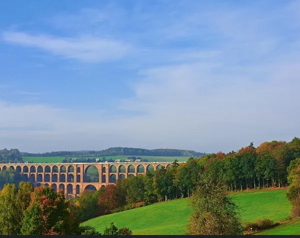 Viadukt im Vogtlandkreis mit herbstlicher Landschaft und blauem Himmel im Hintergrund.