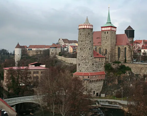 Blick auf die historische Altstadt von Bautzen mit markanten Türmen und einer Brücke im Vordergrund.