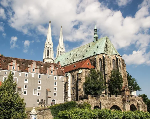 Historisches Gebäude und Kirche in Görlitz unter blauem Himmel mit einigen Wolken.