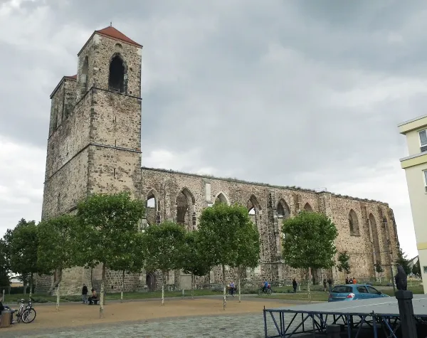 Historische Klosterruine in Anhalt-Bitterfeld mit erhaltenem Kirchenturm und umgebenden Bäumen, bewölkter Himmel.