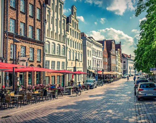 Straßencafé und historische Hausfassaden in der Altstadt von Lübeck bei Sonnenschein.