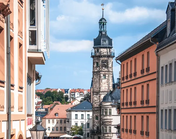 Stadtszene im Altenburger Land mit historischem Kirchturm und umgebender Architektur unter blauem Himmel.