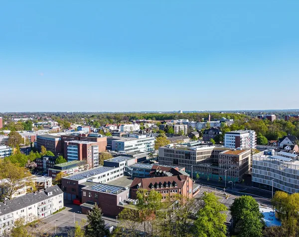 Stadtansicht von Pinneberg mit modernen Gebäuden und grünen Bäumen unter klarem Himmel.
